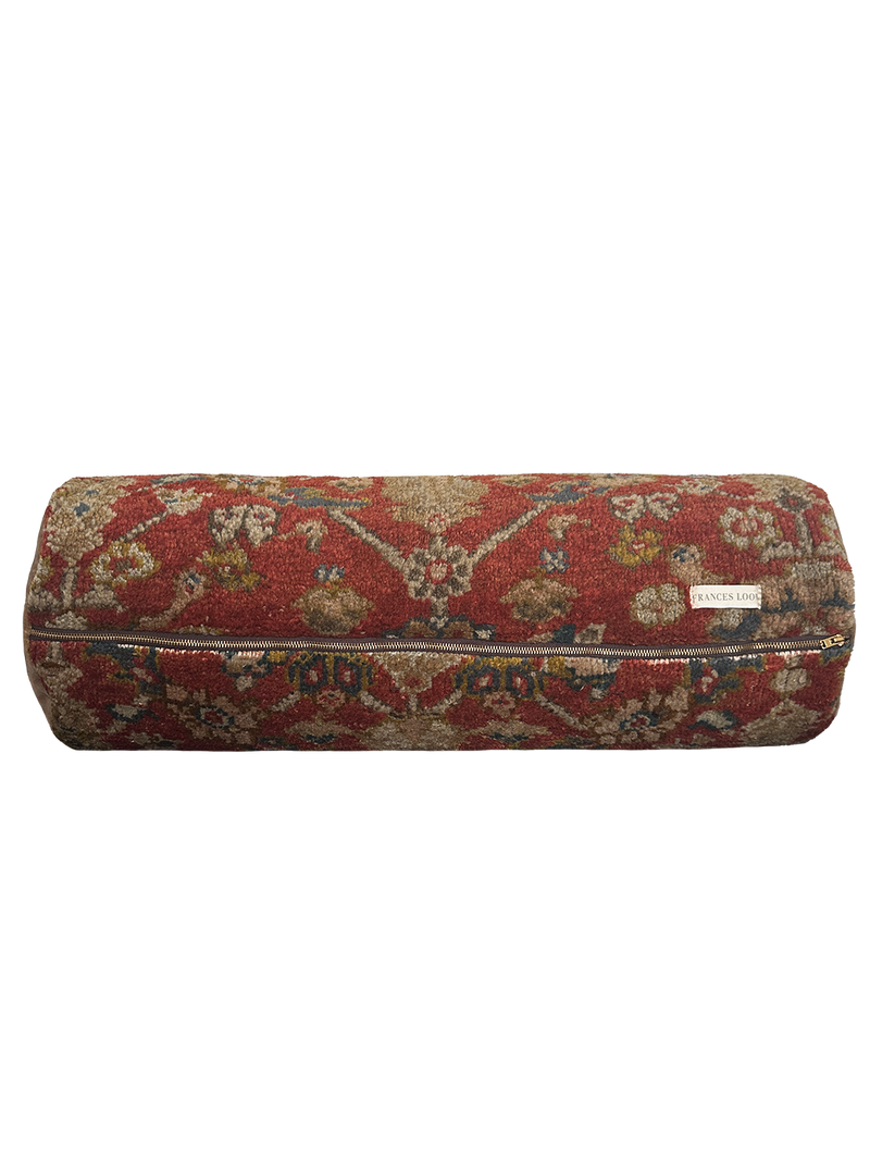 a large bolster cushion made from antique rug with cotton velvet ends