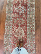 an antique heriz karajah runner with a dark coral field and icy blue and teal accents