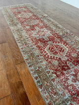 an antique heriz karajah runner with a dark coral field and icy blue and teal accents