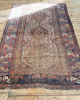 an antique qashqai rug with a cream field and red, pink and blue accents
