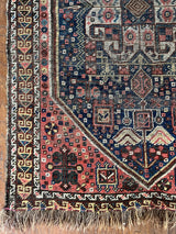a mini antique qashqai rug with a midnight blue field and neon pink accents