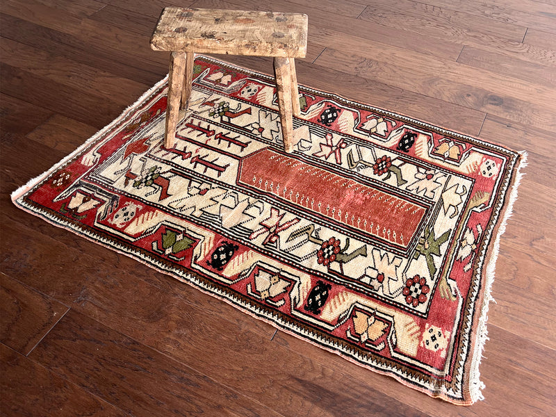 a small turkish milas rug with a salmon pink field and thick ivory border