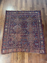 an antique qashqai rug with a dark field and blue, red and ivory accents