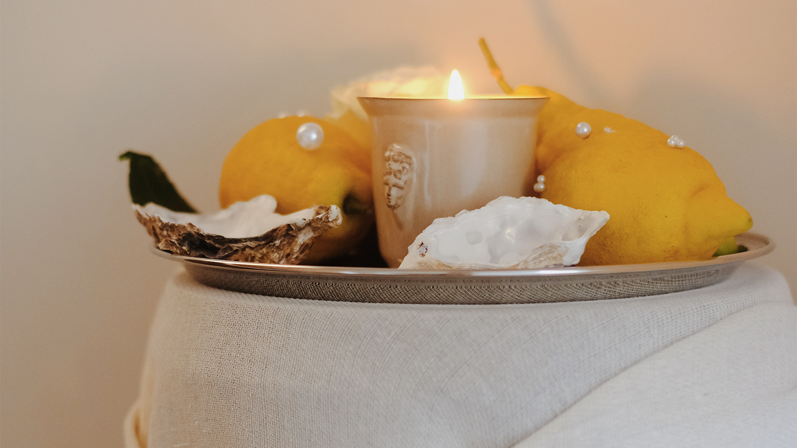 the Muse candle nestled between pearly lemons and oyster shells on a silver tray