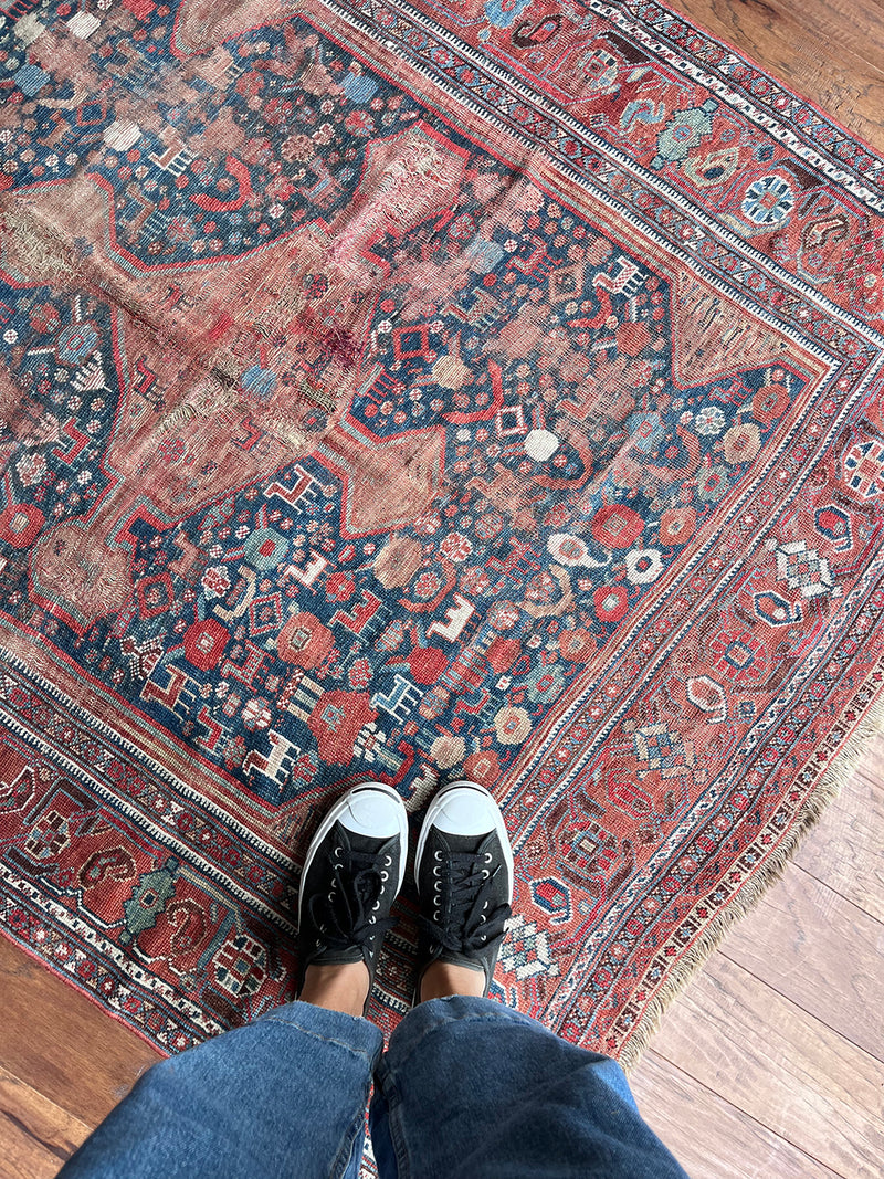 an antique qashqai rug with a blue field and small animal motifs