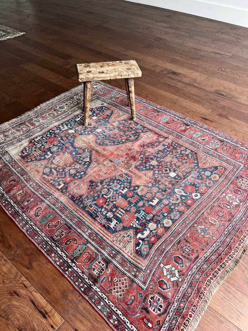 an antique qashqai rug with a blue field and small animal motifs