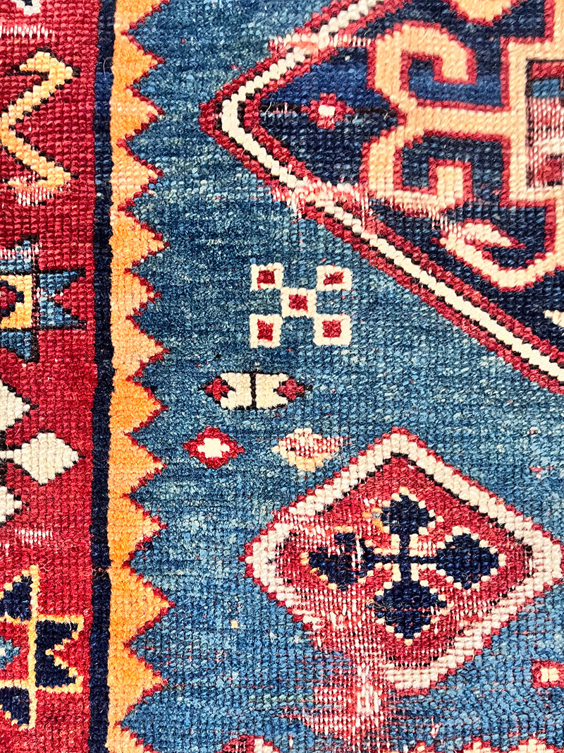 a mini antique kazak rug with a prussian blue field and red and yellow accents