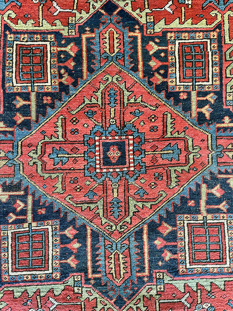 a large antique Heriz rug with a red field and dark blue medallion and border