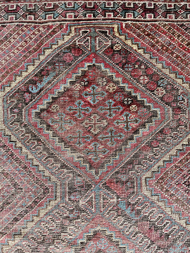 an antique shiraz rug with a unique stripe pattern in pretty primary colors