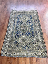 an antique qashqai rug with a dark blue field and taupe medallions with green bird motifs