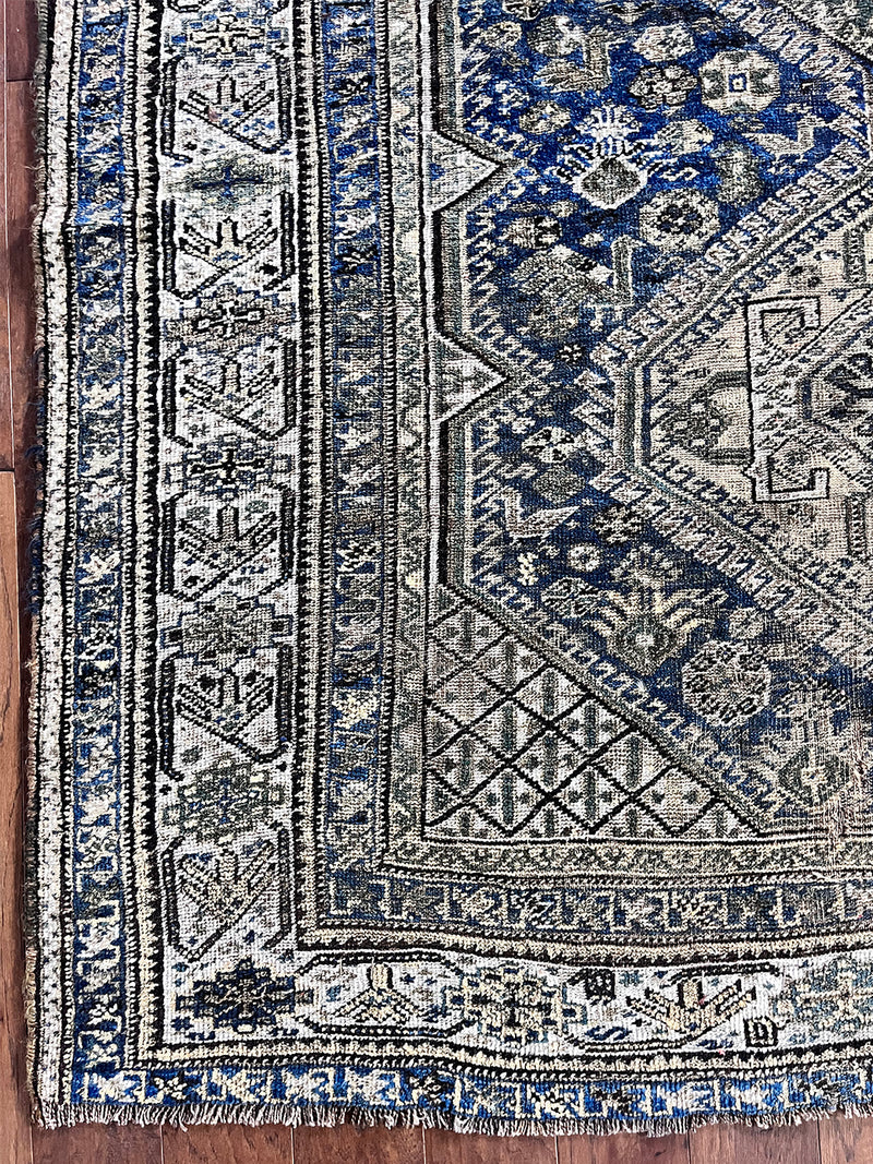 an antique qashqai rug with a dark blue field and taupe medallions with green bird motifs