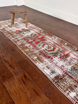 an antique heriz runner with a faded red, blue and brown palette and substantial patina