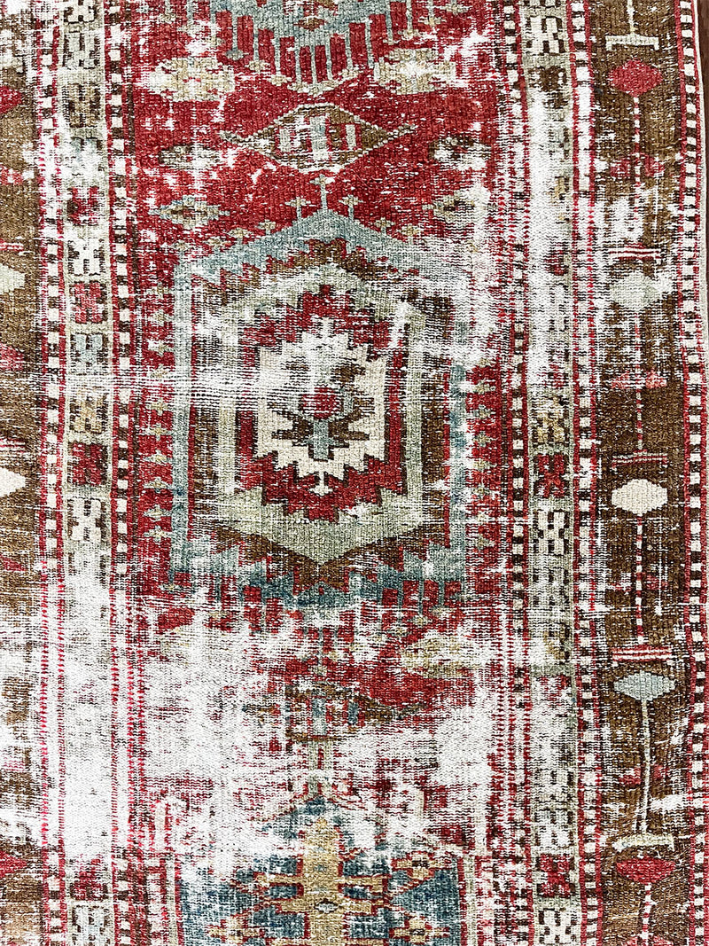 an antique heriz runner with a faded red, blue and brown palette and substantial patina