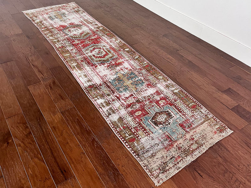 an antique heriz runner with a faded red, blue and brown palette and substantial patina