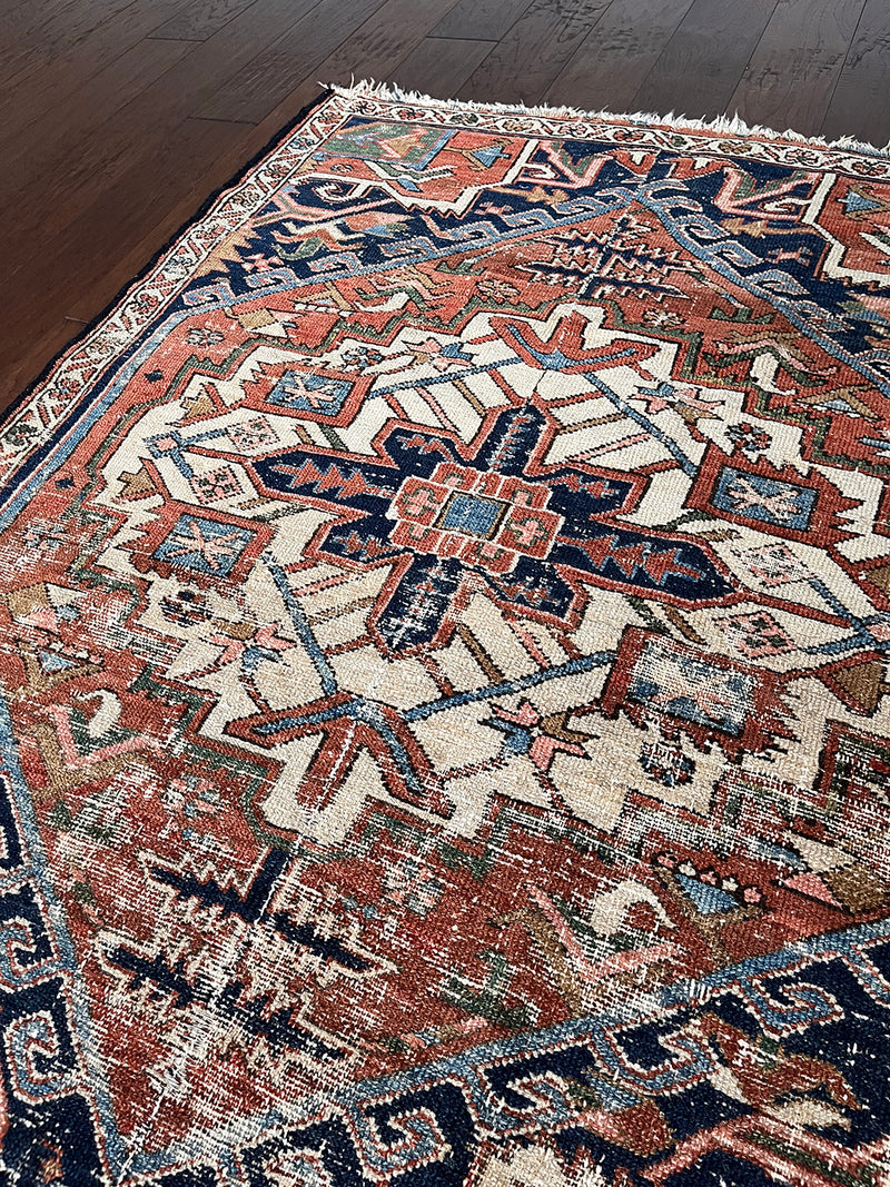 a mini antique heriz rug with a pretty rust field and dark blue, green and salmon pink accents