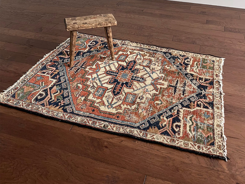 a mini antique heriz rug with a pretty rust field and dark blue, green and salmon pink accents