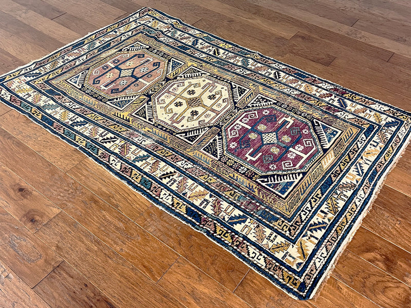 an antique caucasian shirwan rug with lilac, yellow and blue accents and a large cream medallion