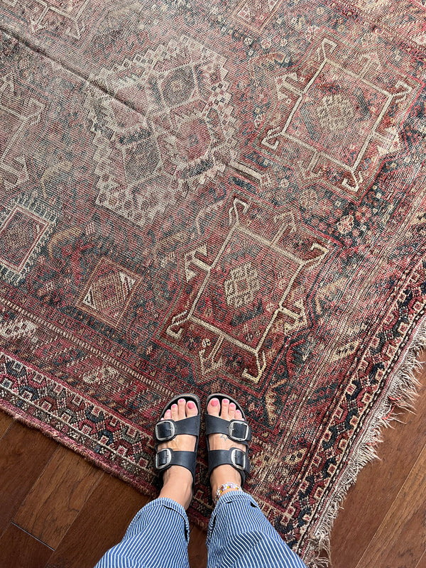 a large shiraz rug with a faded brown palette and soft red accents