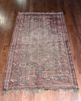 a large shiraz rug with a faded brown palette and soft red accents