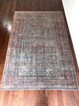 an antique tabriz rug with a teal field, red border and a delicate floral pattern