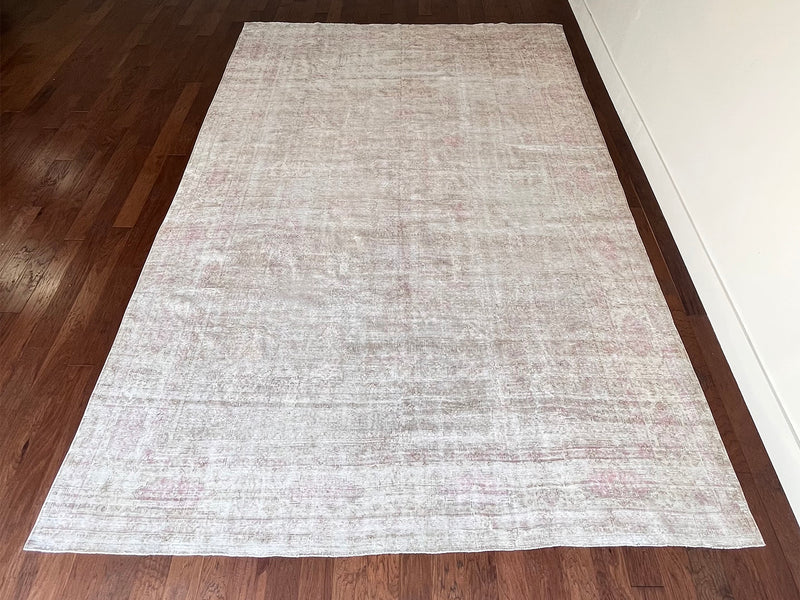 a large faded oushak rug with a soft dusty pink palette and fawn details