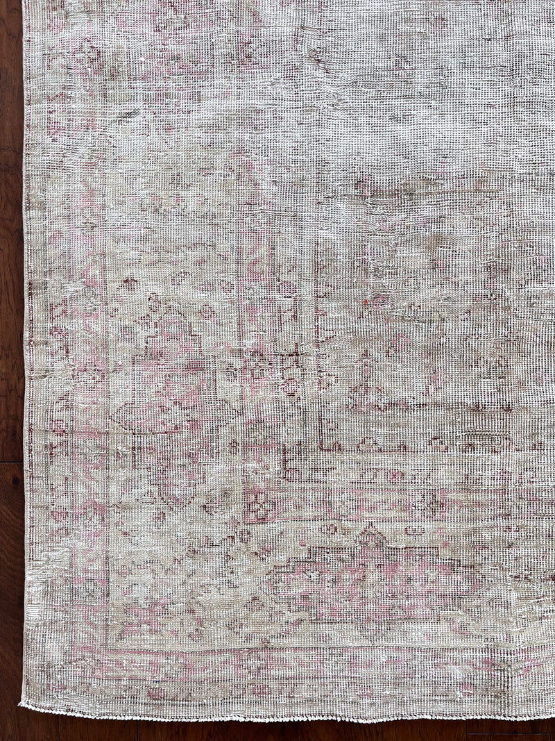 a large faded oushak rug with a soft dusty pink palette and fawn details