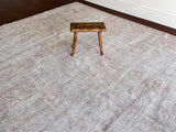 a large faded oushak rug with a soft dusty pink palette and fawn details