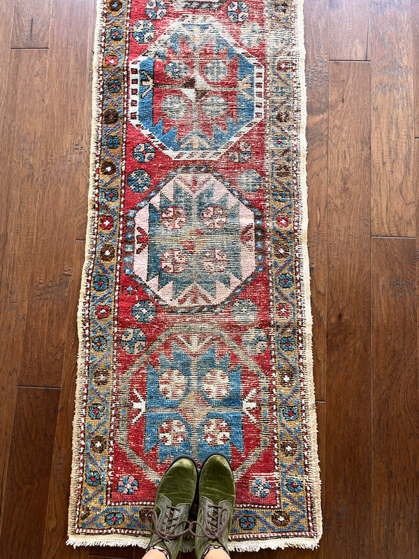 an antique heriz runner with a red field and royal blue medallions