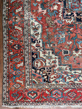 a large antique serapi rug with a coral field and large dark blue medallion