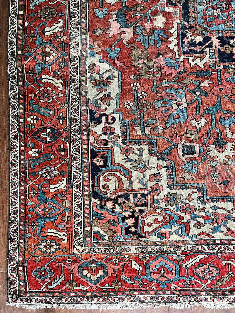 a large antique serapi rug with a coral field and large dark blue medallion