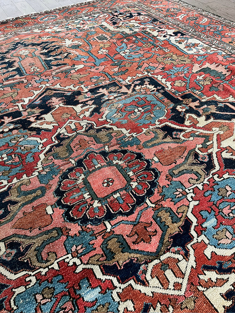 a large antique serapi rug with a coral field and large dark blue medallion