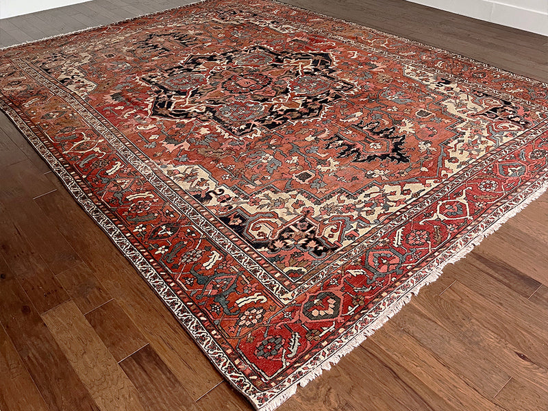 a large antique serapi rug with a coral field and large dark blue medallion