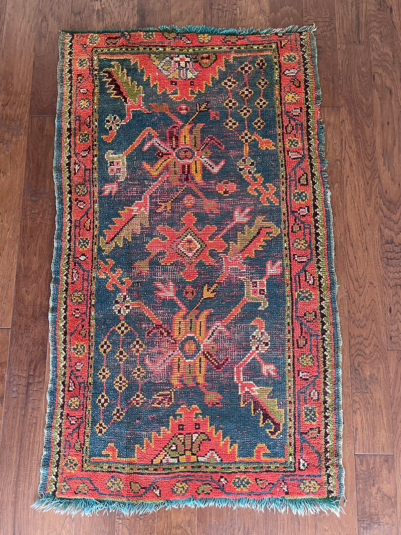 an antique oushak rug with a dark blue field and a red, orange and lime green pattern