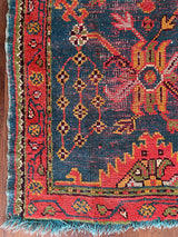 an antique oushak rug with a dark blue field and a red, orange and lime green pattern