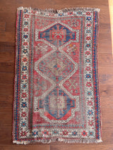 an antique caucasian rug with a rusty red field and blue medallions