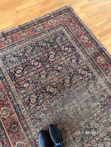 an antique farhan rug with a dark blue field and a red floral pattern