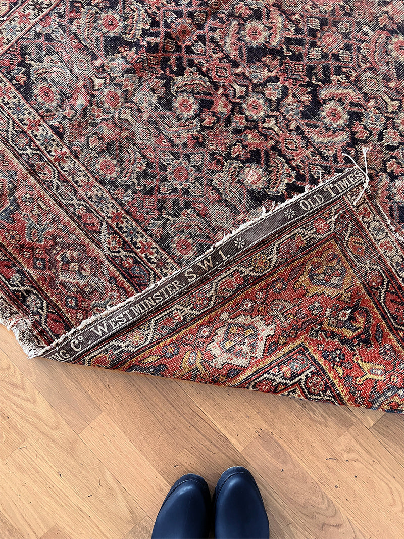 an antique farhan rug with a dark blue field and a red floral pattern