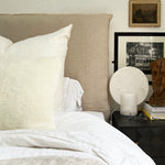 a white shearling pillow backed in plush velvet, with an exposed brass zipper