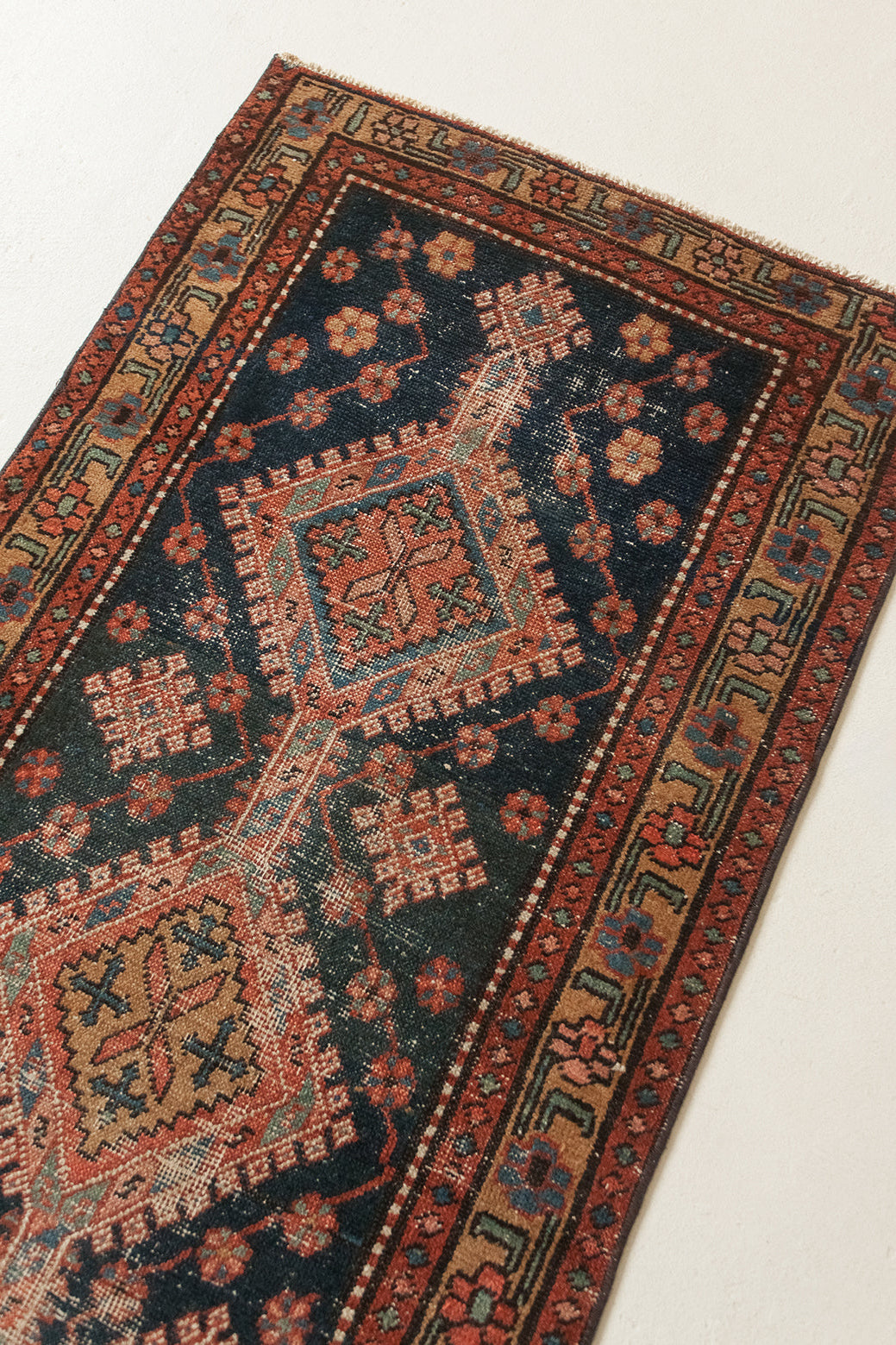 A traditional Persian-style area rug with a dark navy blue field, featuring large central medallions in rust red, beige, and orange, surrounded by a patterned border.