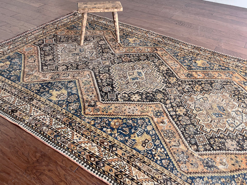 an antique qashqai rug with a dark blue, black and orange palette and small animal motifs
