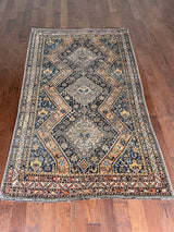 an antique qashqai rug with a dark blue, black and orange palette and small animal motifs