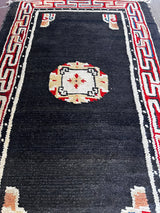 a small tibetan rug with a black field and a pretty red and yellow geometric design
