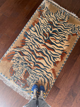 a vintage chinese rug with a large graphic tiger design in blue and burnt orange stripes