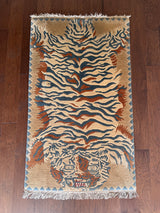 a vintage chinese rug with a large graphic tiger design in blue and burnt orange stripes