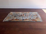 a vintage chinese rug with a large graphic tiger design in blue and burnt orange stripes