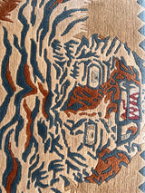 a vintage chinese rug with a large graphic tiger design in blue and burnt orange stripes