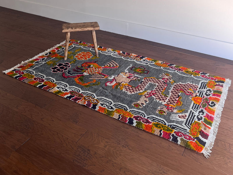 a vintage tibetan rug with a silky grey and field and a bright orange and coral dragon motif