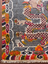 a vintage tibetan rug with a silky grey and field and a bright orange and coral dragon motif