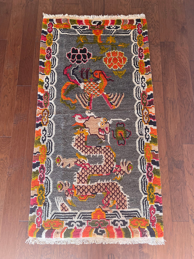 a vintage tibetan rug with a silky grey and field and a bright orange and coral dragon motif