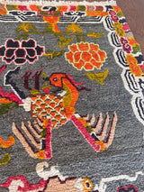 a vintage tibetan rug with a silky grey and field and a bright orange and coral dragon motif